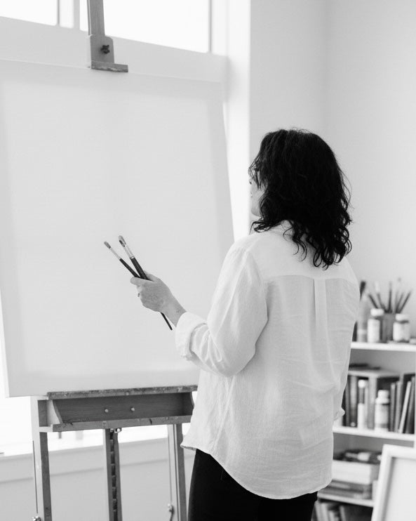 Elizabeth Ortiz painting on a large canvas in an art studio.
