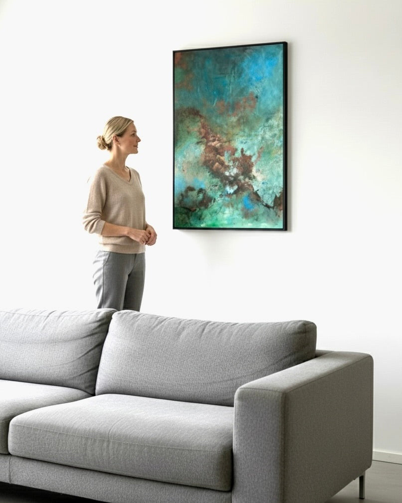 Woman standing in a living room looking at a large abstract painting on the wall.