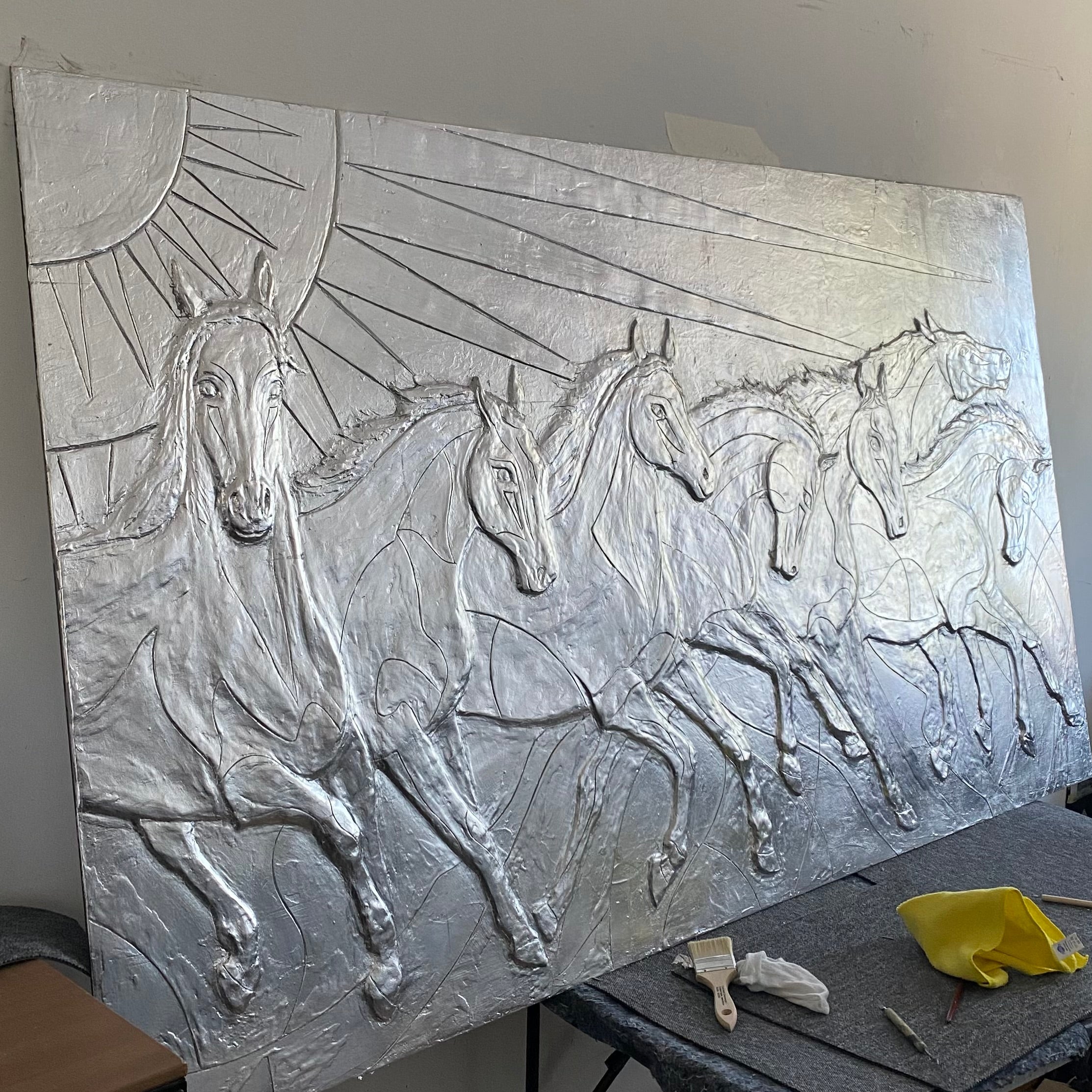 Metallic sculpture of horses on a textured surface