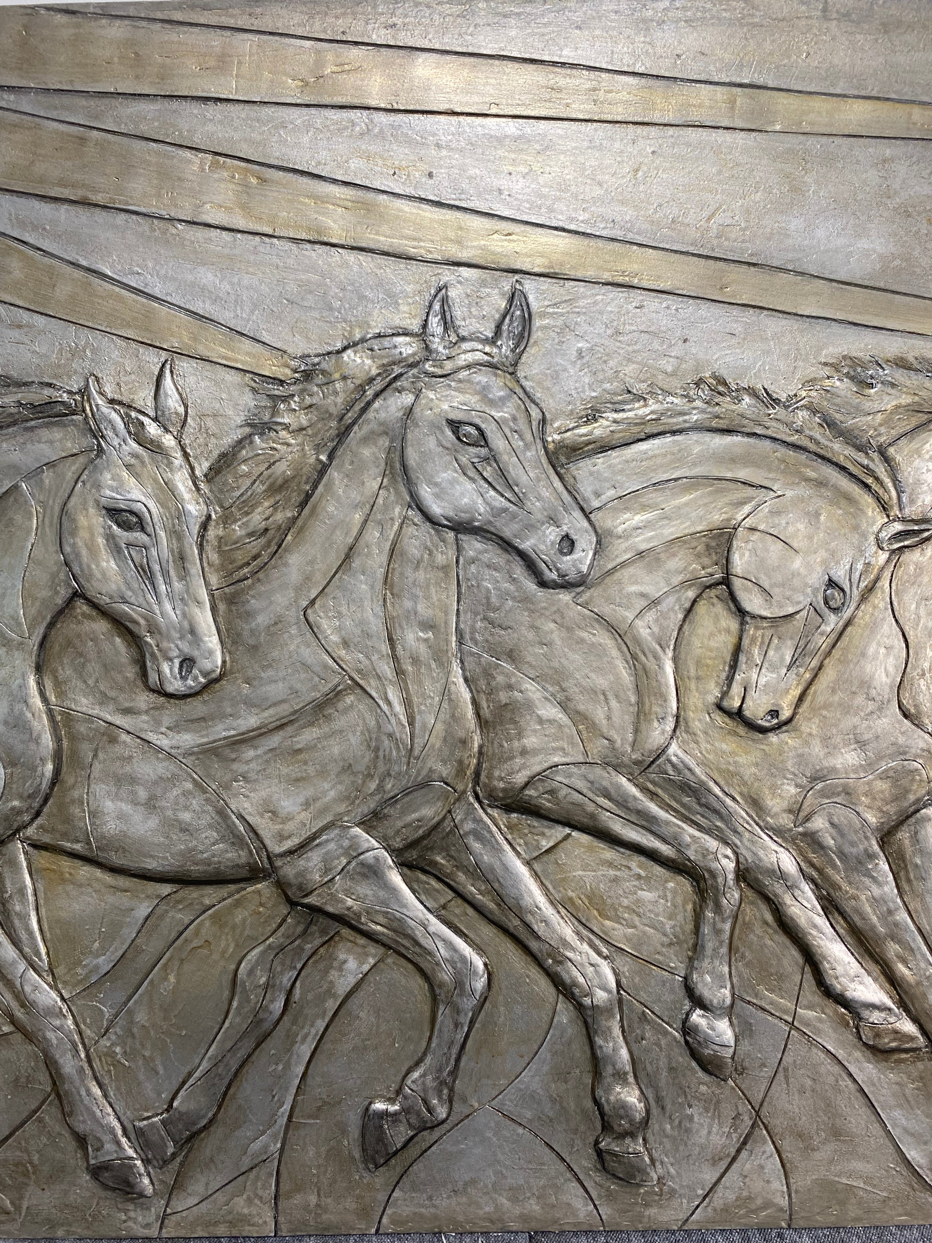 Metallic relief sculpture of horses on a textured background
