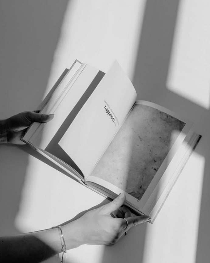 Person holding an open book with a shadowy background. Image credit: Elisabeth Wittauer.