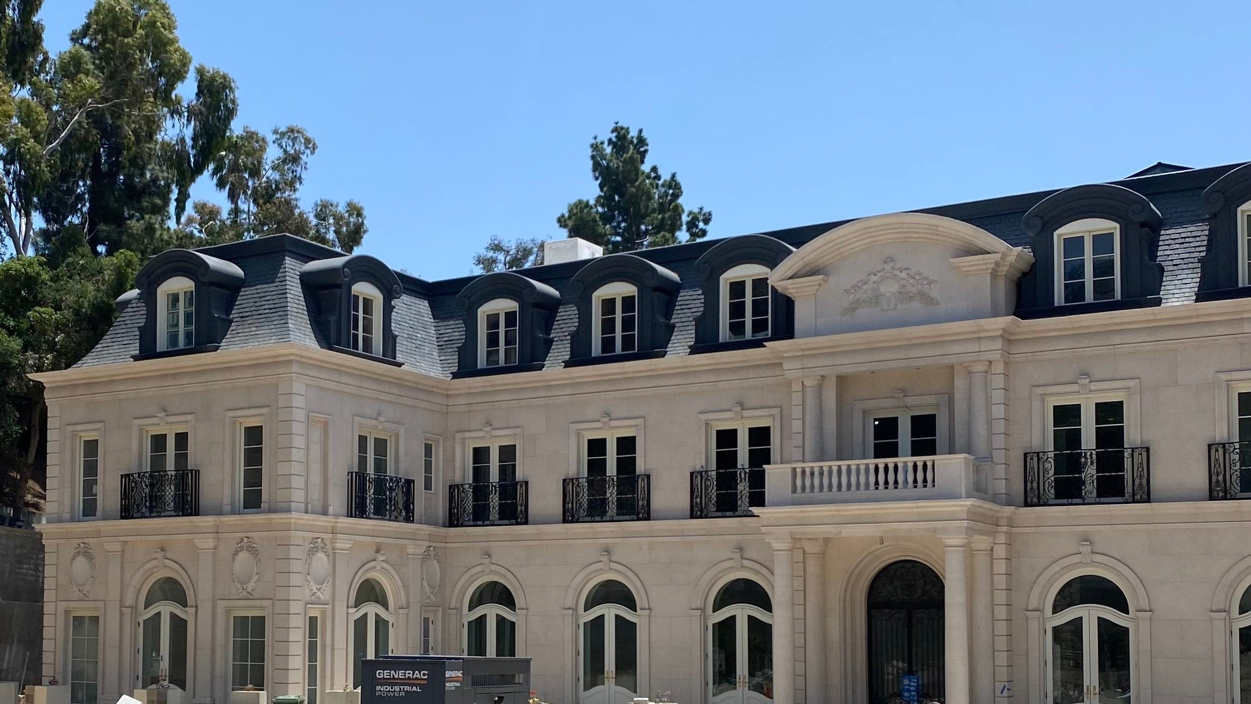 Large mansion under construction with trees and blue sky in the background