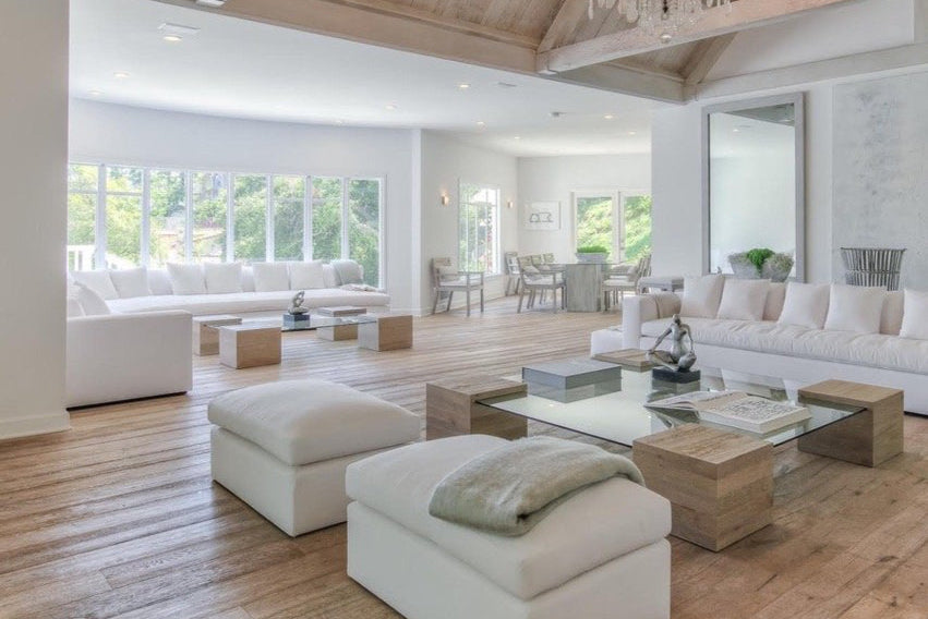 Modern living room with white furniture, wooden floor, and chandelier.